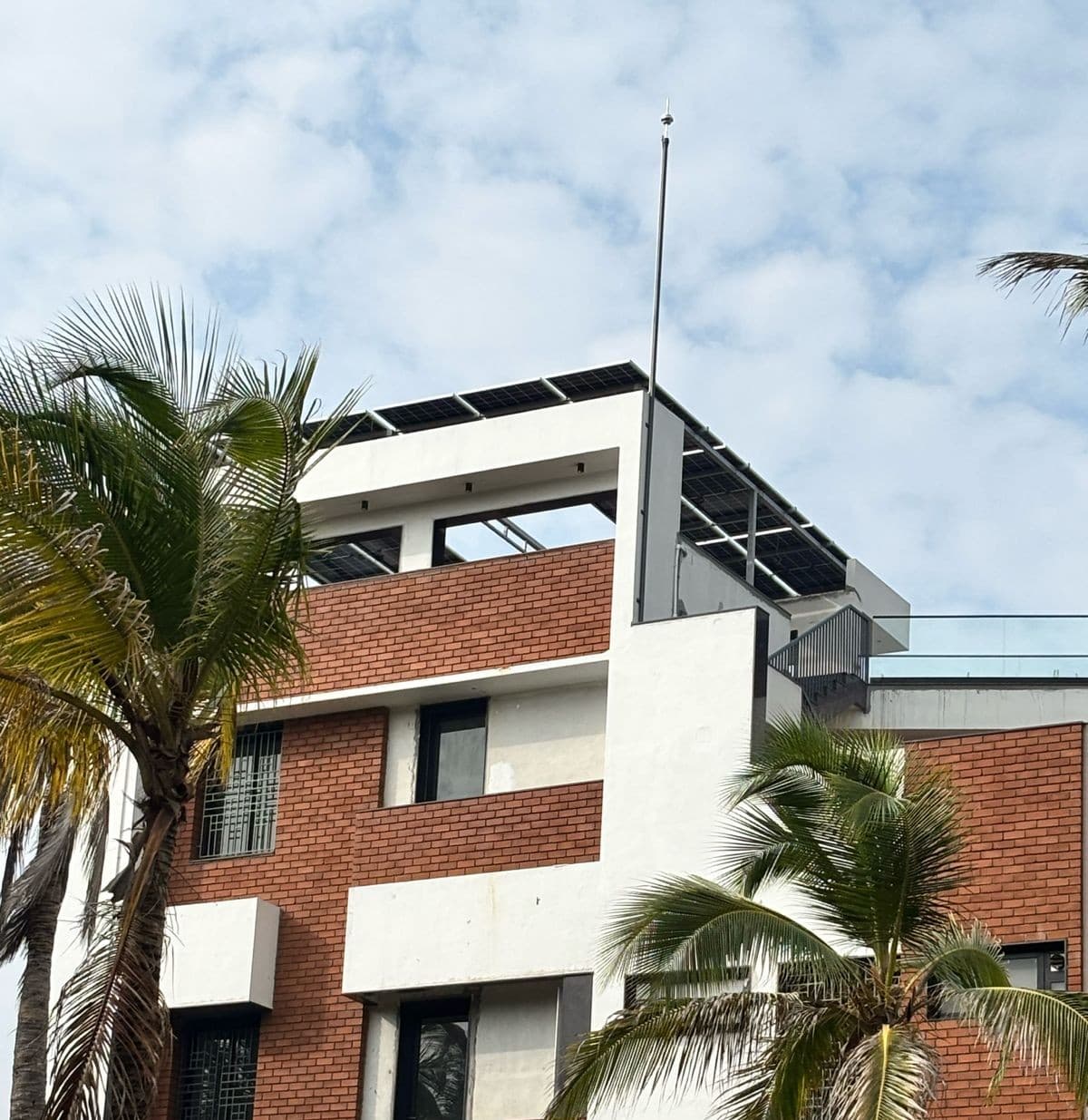 Lightning arrester mast installed on a residential building rooftop with solar panels